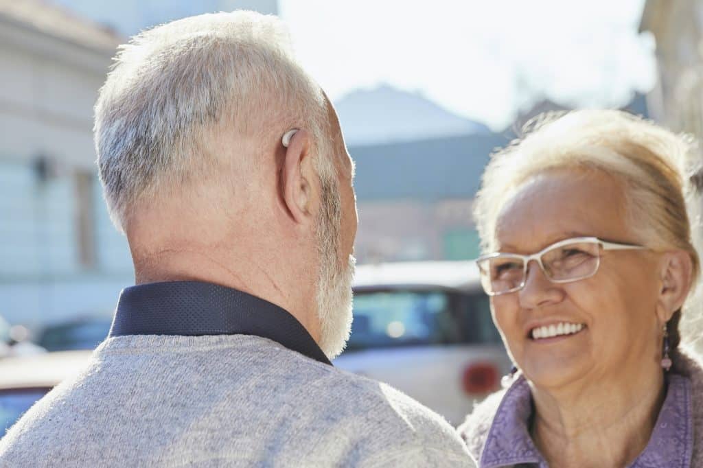 Close-up of senior man with hearing aid talking to senior woman